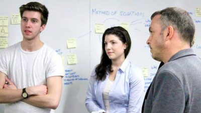 Three people talking in front of a whiteboard