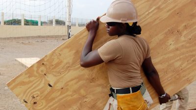 A construction worker carrying a large piece of plywood