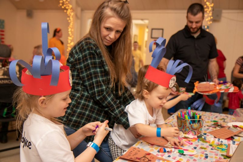 Two children in homemade Seuss hats make a craft using glue sticks and colorful markers.