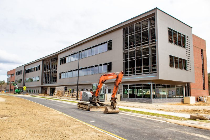 Tech Center Research Park A partially constructed modern three-story office building with construction equipment sitting in the foreground.