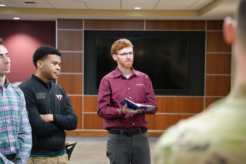 Boeing employee holding a book and speaking to students with feedback.