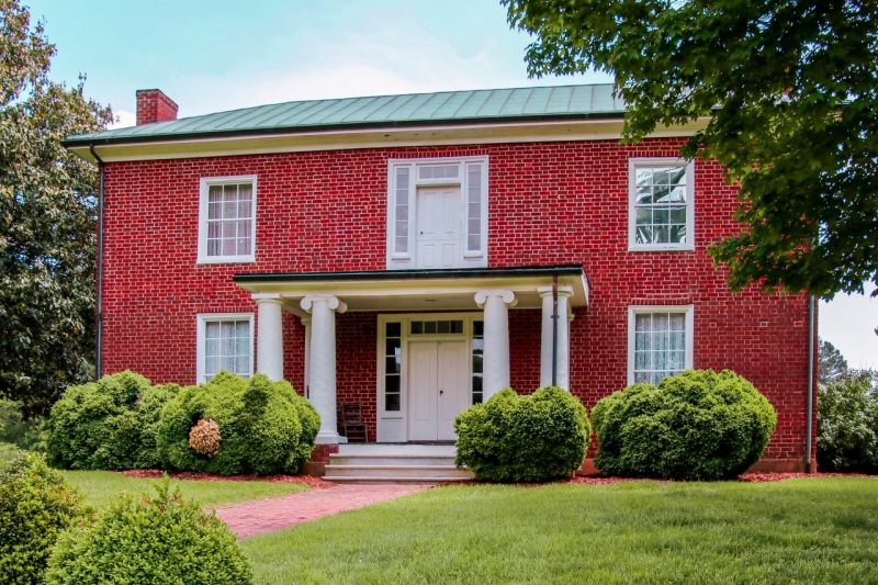 A old brick house with white pillars.