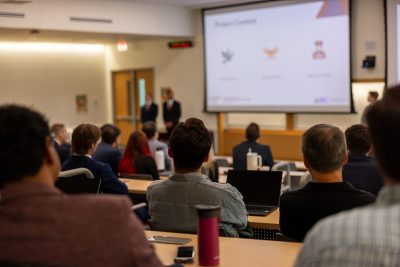 Attendees watch as students from the MSBA-BA program give their capstone presentation.