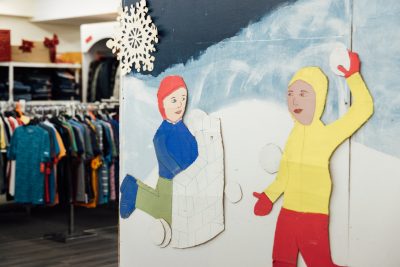 On a wall is a paper decoration of two children in a snowball fight.