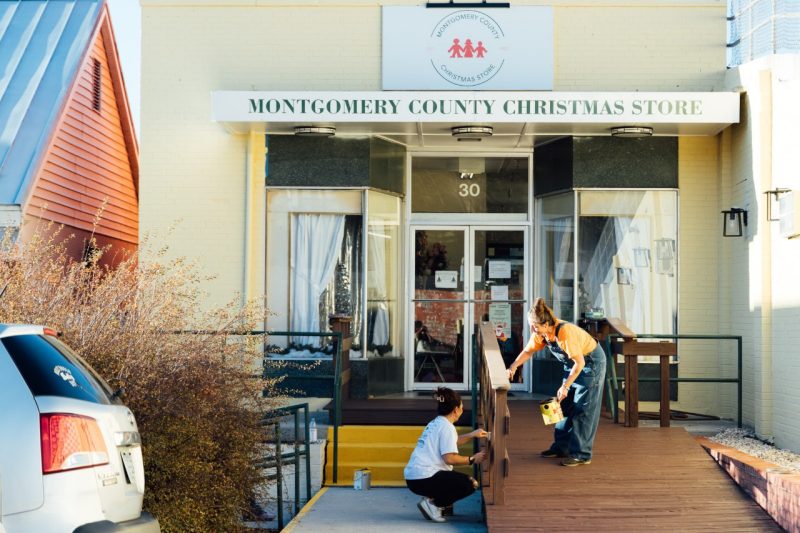Two volunteers do work on wooden railings near the front entrance of the Montgomery County Christmas Store.