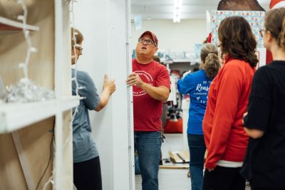 With several volunteers watching, John Tarter holds a shelf under construction.