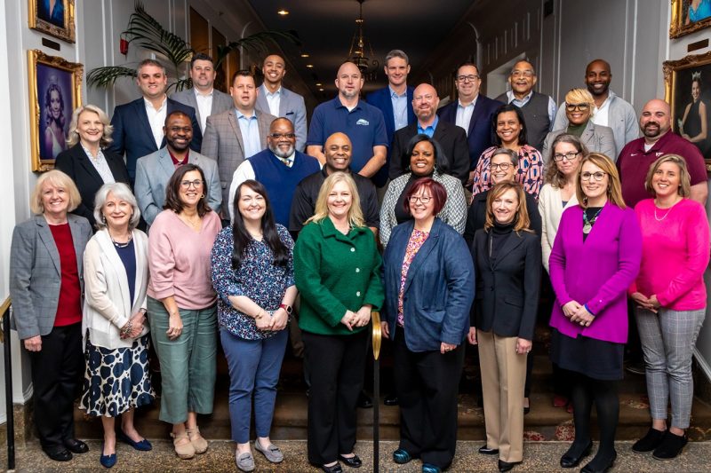 A group photo of about 25 participants standing on stairs in a hallway.