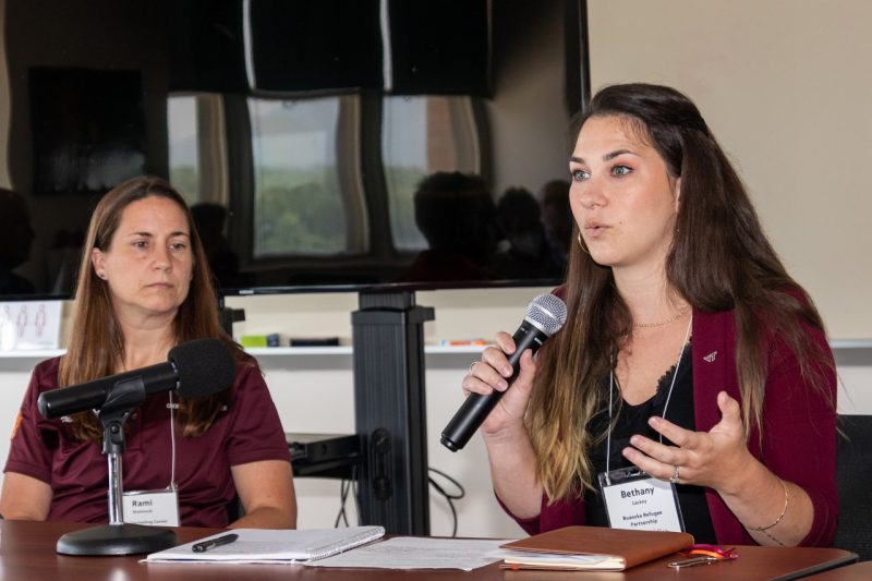 A woman speaks into a microphone while another listens