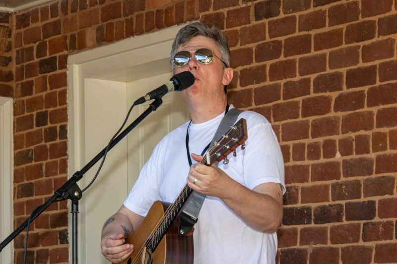 A man with a guitar sings at a microphone