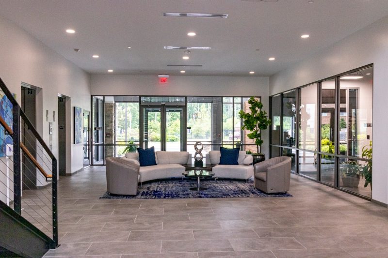 A white couch in the middle of an office building lobby.