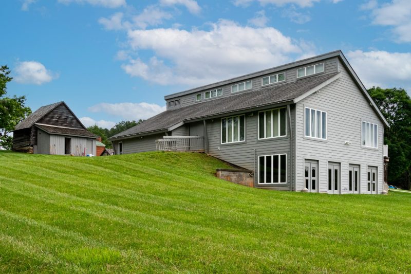A gray building with big vertical windows in a big, green lawn.