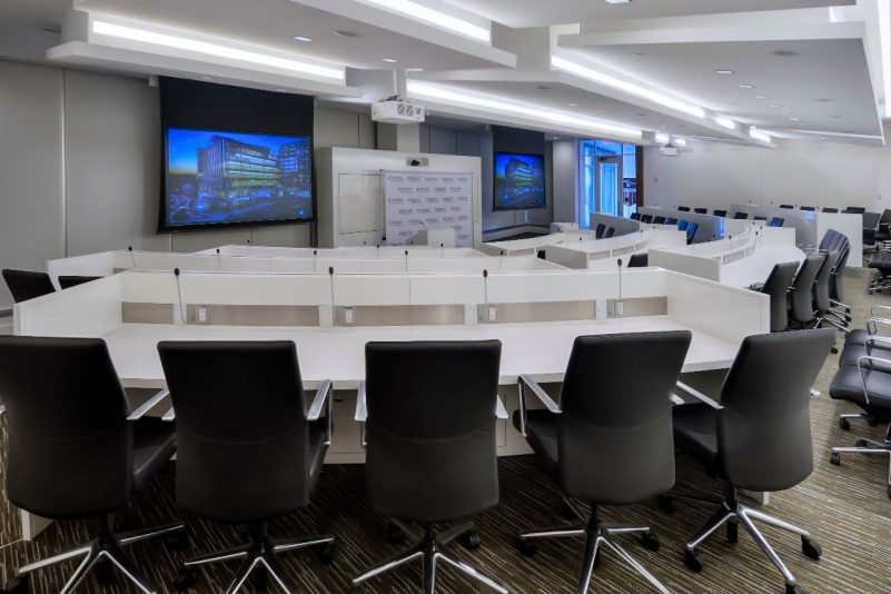 A tiered conference room with giant TV screens at the front.