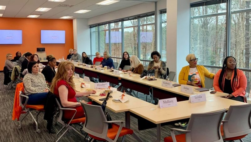 Women gathered around a long table in a classroom