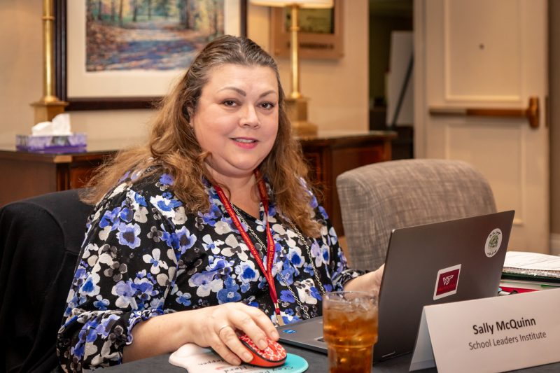 Sally McQuinn sits at a desk in front of a laptop computer.