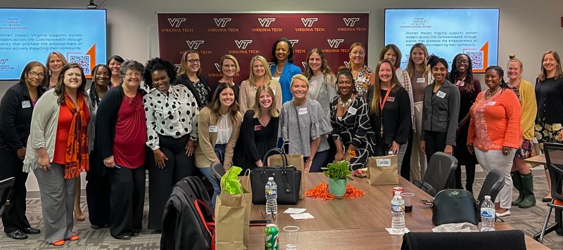 A large group photo in from of a maroon backdrop filled with Virginia Tech logos.